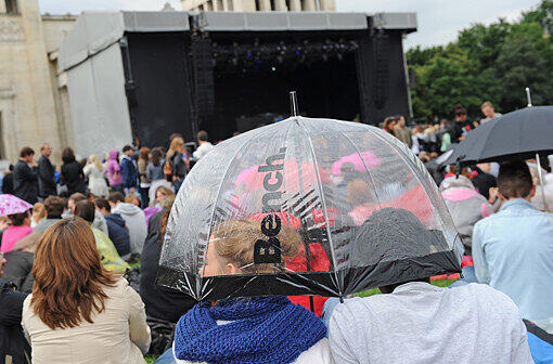 Schutz vor dem Regen unter einem Schirm: Besucher des David-Guetta-Auiftritts auf dem Königsplatz in München.