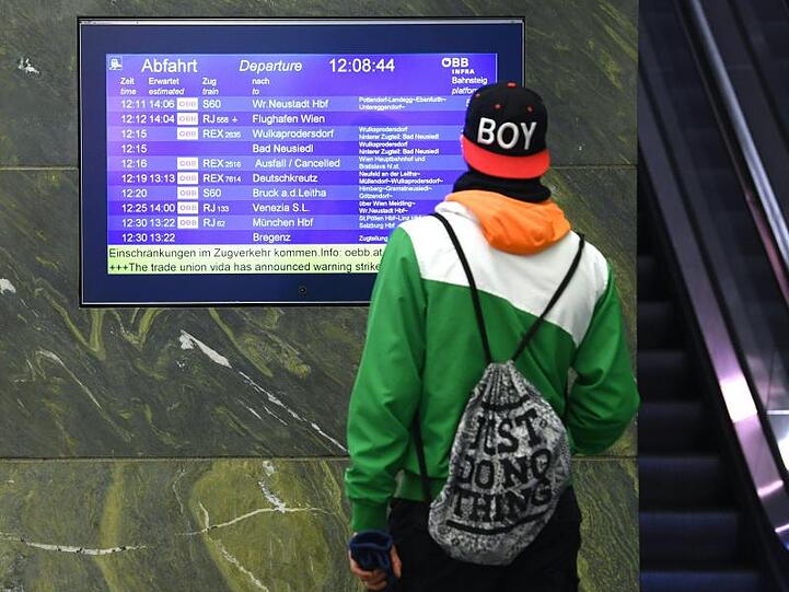 Ein Mann steht vor einer Anzeigetafel am Westbahnhof, die über den eingestellten Zugverkehr informiert. Foto: Helmut Fohringer