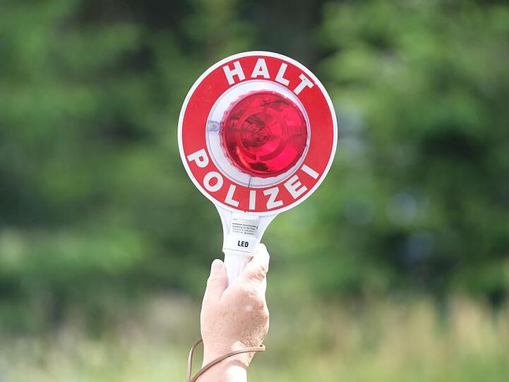 Eine Polizistin hält während einer Polizeikontrolle eine rote Winkerkelle in die Höhe. Foto: Sebastian Willnow/zb/dpa/Archivbild
