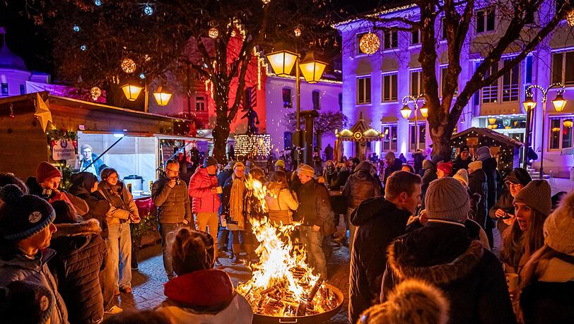 Winterzauber in Holzkirchen – mit Feuerschale, Beleuchtung und Menschen, die einen heißen Glühwein genießen.