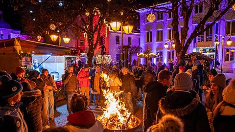 Winterzauber in Holzkirchen – mit Feuerschale, Beleuchtung und Menschen, die einen heißen Glühwein genießen.