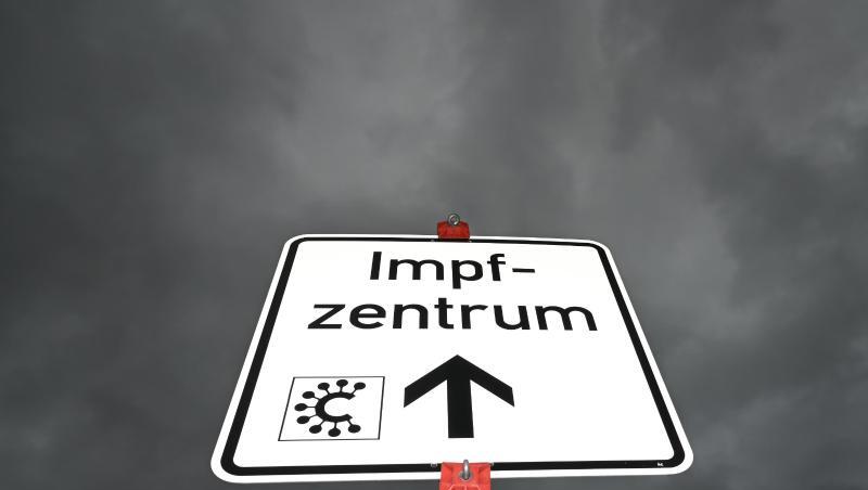 Ein Hinweisschild mit der Aufschrift "Impfzentrum" und einem Covid-Logo ist nahe des Impfzentrums Heuchelheim zu sehen.