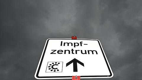Ein Hinweisschild mit der Aufschrift "Impfzentrum" und einem Covid-Logo ist nahe des Impfzentrums Heuchelheim zu sehen.