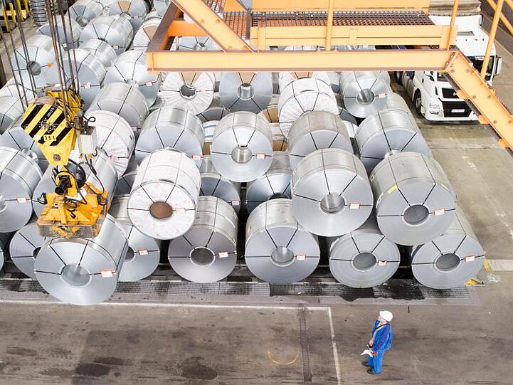 Ein Mitarbeiter transportiert mit einem Kran auf dem Gelände der Salzgitter AG Coils (aufgewickelte Metallbänder).