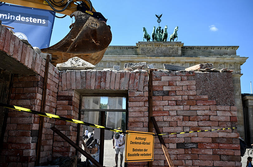 Ein Bagger, an dem ein Banner mit der Aufschrift „Jeden Tag geht in Deutschland mindestens ein Denkmal verloren“ hängt, steht in einer aufgebauten Kulisse vor dem Brandenburger Tor. Die Deutsche Stiftung Denkmalschutz (DSD) möchte auf den Verlust und die Bedrohungen in der deutschen Denkmallandschaft aufmerksam machen.