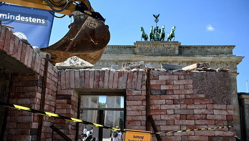 Ein Bagger, an dem ein Banner mit der Aufschrift „Jeden Tag geht in Deutschland mindestens ein Denkmal verloren“ hängt, steht in einer aufgebauten Kulisse vor dem Brandenburger Tor. Die Deutsche Stiftung Denkmalschutz (DSD) möchte auf den Verlust und die Bedrohungen in der deutschen Denkmallandschaft aufmerksam machen.