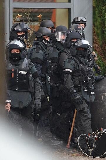 Mit erhobenen Händen kommt ein Mann auf die SEK-Beamten zu, im Hintergrund lauern Heckenschützen der Polizei. Die Beamten nehmen den Mann fest, es ist aber nicht der Täter, der sich in einem Imbiss in Freiburg veschanzt hat.