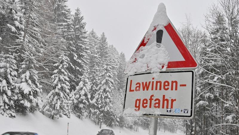 PKW fahren an einem "Lawinengefahr"-Schild vorbei.