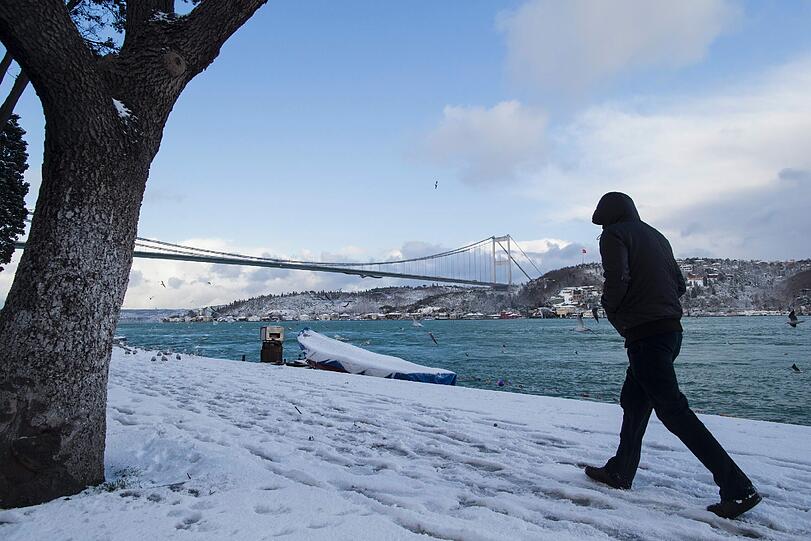 In Istanbul hat ein Wintereinbruch Teile des öffentlichen Lebens zum Erliegen gebracht. Hier schlendert ein Mann die verschneite Uferpromenade entlang.