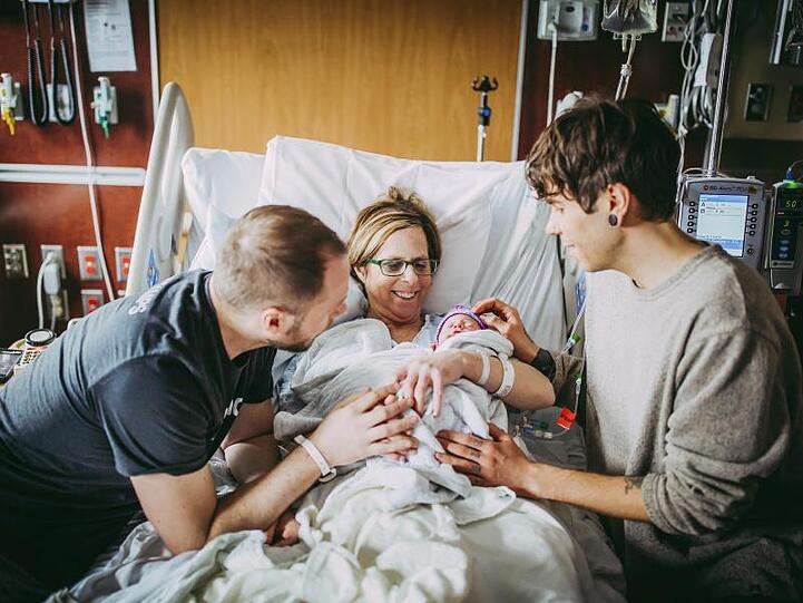 Matthew Eledge (l), seine Mutter Cecile Eledge und Matthews Mann, Elliot Dougherty, heißen Baby Uma nach ihrer Geburt willkommen.