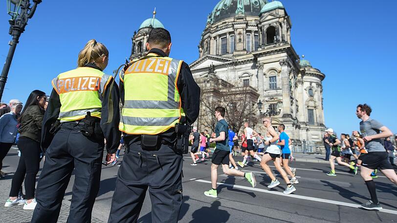 Zwei Polizisten stehen an der Halbmarathonstrecke in Berlin vor dem Dom.