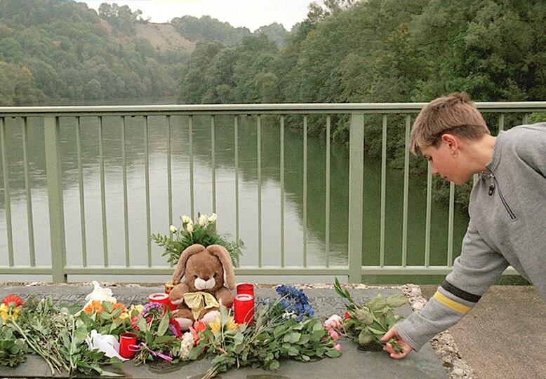 Ein Junge legt eine Blume an der Lechbrücke nieder.