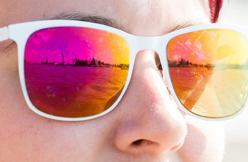 Die Kulisse des Hamburger Hafens spiegelt sich in der Sonnenbrille einer Frau. Foto: Daniel Reinhardt