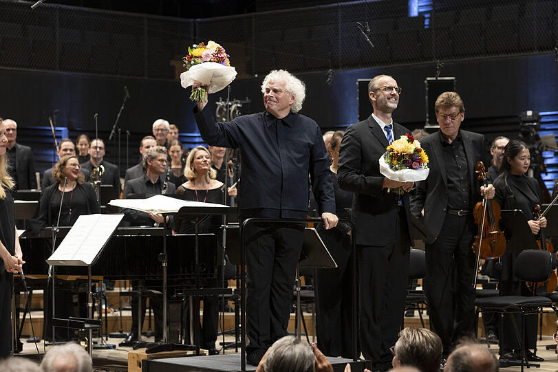 Simon Rattle und der Chorleiter Peter Dijkstra beim Schlussapplaus. Hinten der Bratschist Hermann Menninghaus.