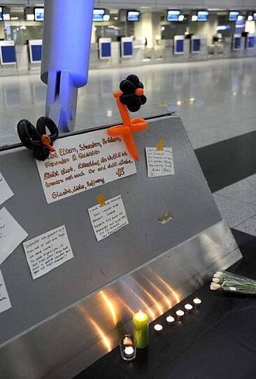 Am Flughafen in Düsseldorf schreiben Menschen Kondolenzbotschaften für die Absturzopfer an eine Tafel