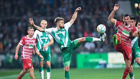 Werders Mitchell Weiser (l) kämpft im Hinspiel gegen Augsburgs Mergim Berisha um den Ball.