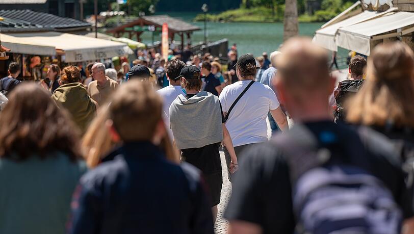 Touristen laufen eine Strasse zum Königssee hinunter. (Archivbild)