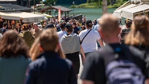Touristen laufen eine Strasse zum Königssee hinunter. (Archivbild)