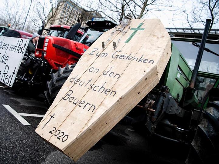 Ein Sarg mit Aufschrift und ein Schild während einer Demonstration der Landwirte an Treckern. Foto: Matthias Balk/dpa