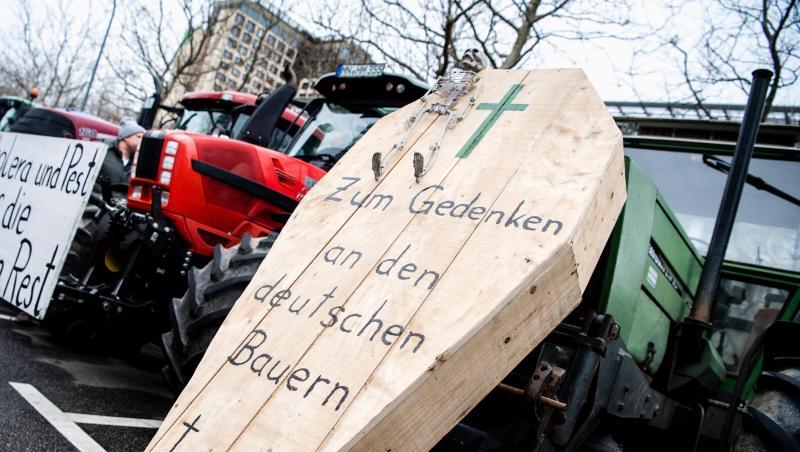 Ein Sarg mit Aufschrift und ein Schild während einer Demonstration der Landwirte an Treckern. Foto: Matthias Balk/dpa