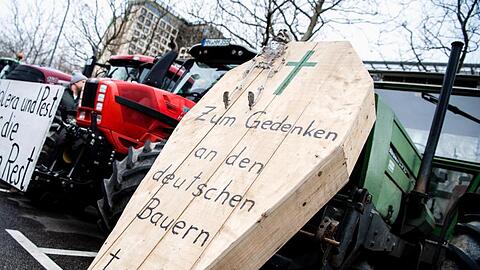 Ein Sarg mit Aufschrift und ein Schild während einer Demonstration der Landwirte an Treckern. Foto: Matthias Balk/dpa