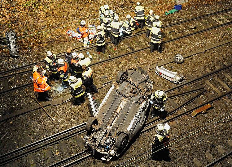 Das Auto liegt auf den Gleisen, die Feuerwehr kümmert sich um die Bergung.