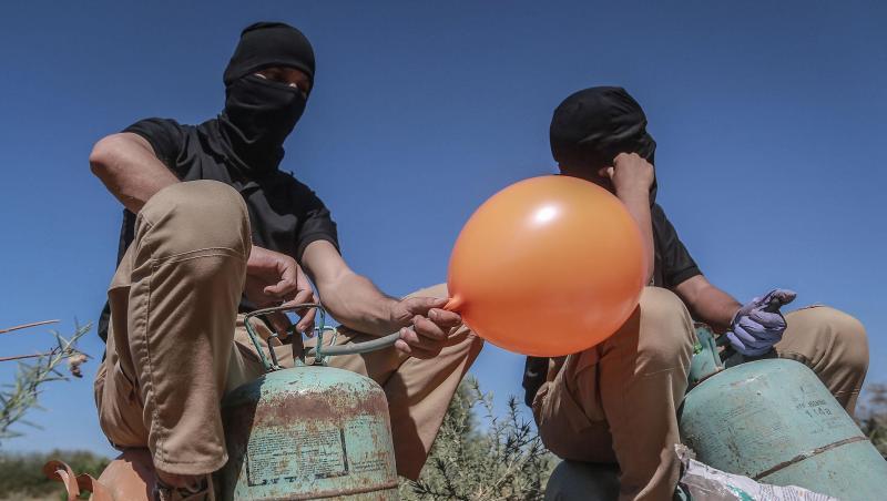 Maskierte Palästinenser präparieren Brandballons. Maskierte Palästinenser präparieren Brandballons.