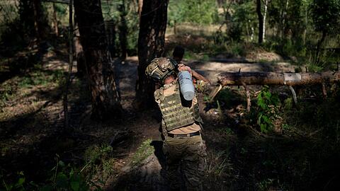 Ein ukrainischer Soldat trägt eine Granate in Richtung einer Haubitze an der Frontlinie bei Lyman.