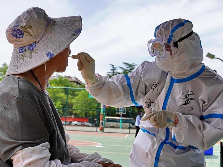 Ein medizinischer Mitarbeiter entnimmt einem Bürger von Peking eine Probe.