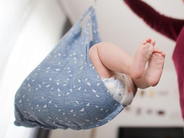 Eine Hebamme wiegt im Rahmen der Nachsorge ein Baby. Foto: Julian Stratenschulte/dpa/Archivbild