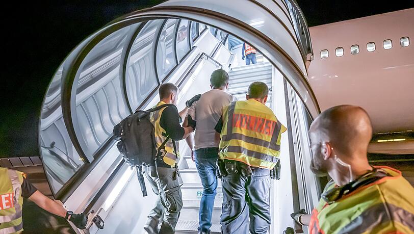 Polizeibeamte begleiten einen abgewiesenen Asylbewerber am Flughafen zu einem Charterflugzeug. 	Foto: dpa
(Archivbild)