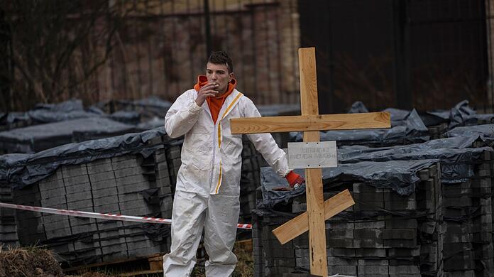 Ein Friedhofsarbeiter macht eine Pause von der Arbeit an einem Massengrab in Butscha.