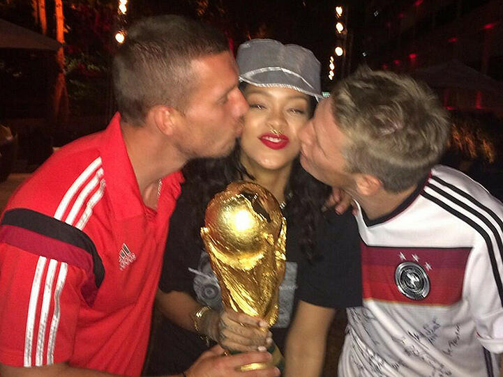 Freut sie sich über den Pokal oder die Küsse: Rihanna zwischen Lukas Podolski (l.) und Bastian Schweinsteiger