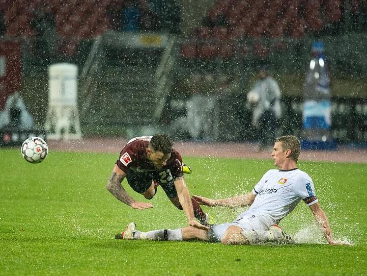 Der Leverkusener Lars Bender (r) grätscht gegen den Nürnberger Tim Leibold.