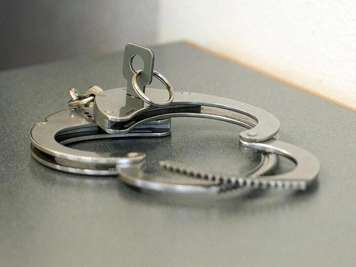 Handschellen liegen auf einem Tisch. Foto: Armin Weigel/dpa/Symbolbild