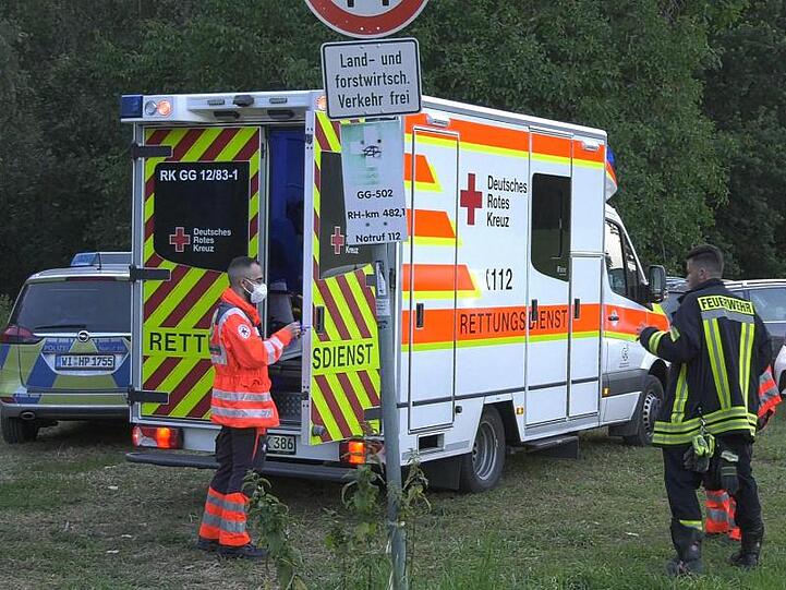 Rettungskräfte stehen am Ufer des Rheins bei Trebur.