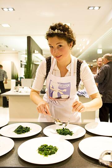 Maria Krieger mit ihrer &bdquo;Bierkönigin&ldquo;-Krone beim Spinat Anrichten. Hier ahnt noch niemand, dass sie am Ende auch Koch-Königin wird.