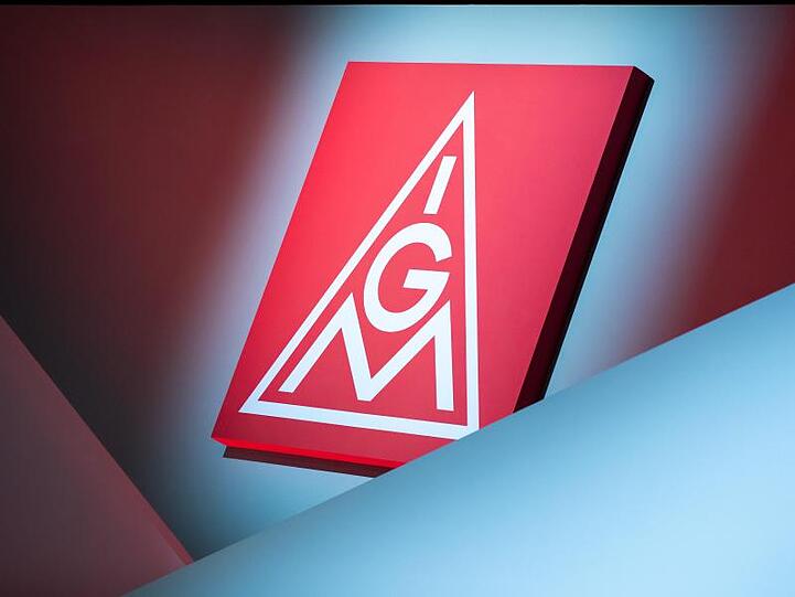 Das Logo der IG Metall hängt über eine Bühne. Foto: Daniel Karmann/dpa/Symbolbild