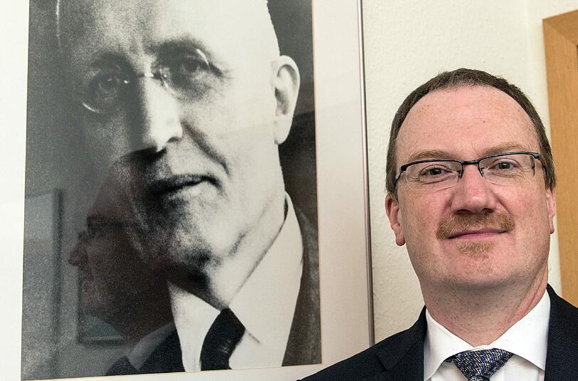 Lars Peter Feld, Leiter des Walter Eucken Instituts in Freiburg, vor einem Portrait des Freiburger Wirtschaftswissenschaftlers.