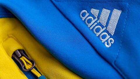 Das Logo des Sportartikelherstellers adidas auf einer blau-gelben Jacke.