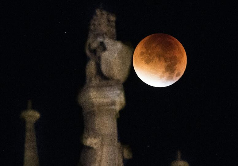 Dunkelrot glimmte der Mond neben einer Löwenfigur auf einer der Zinnen des Rathauses in München.