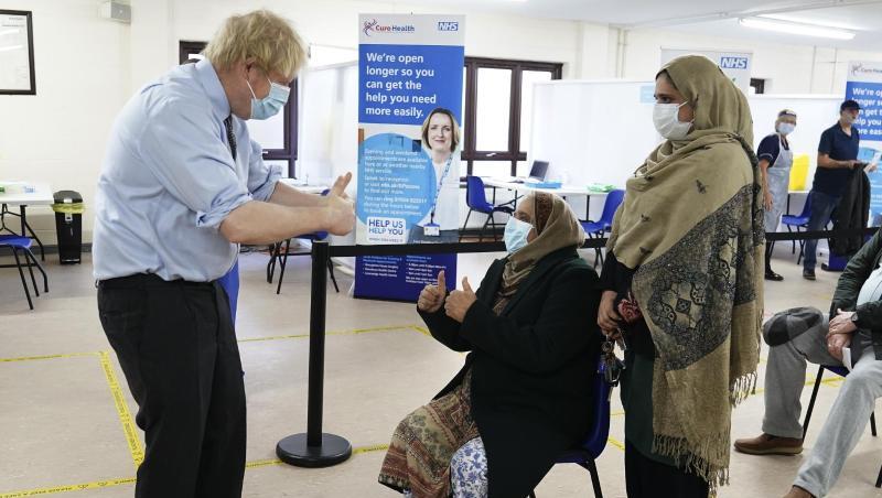 Premierminister Boris Johnson (l.) zeigt bei einem Besuch in einem Impfzentrum den Patienten den Daumen nach oben.