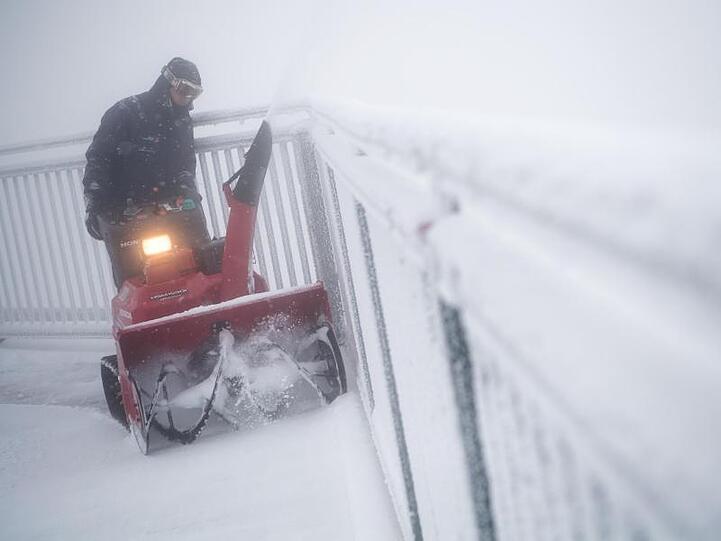Ein Mann fährt mit einem Schneepflug auf dem Gipfel der Zugspitze über die Aussichtsplattform. Foto: Sven Hoppe/Archivbild