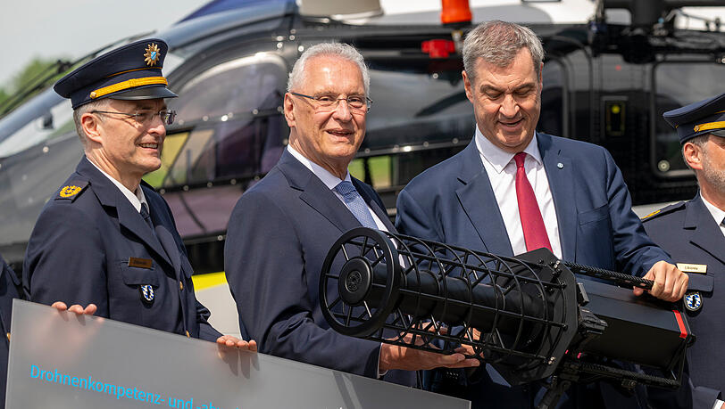 Michael Dibowski (l-r), Pr&auml;sident der Bayerischen Bereitschaftspolizei, Joachim Herrmann, (CSU) Staatsminister des Innern, f&uuml;r Sport und Integration, und Markus S&ouml;der, (CSU) Ministerpr&auml;sident von Bayern, nehmen an der Er&ouml;ffnung des Drohnenkompetenz- und -abwehrzentrum teil. In den H&auml;nden halten sie einen "Counter LAV Jammer HP 47 + PR V7" zur Drohnenabwehr.