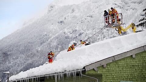 Januar 2019 in Inzell: Feuerwehrleute räumen den Schnee vom Dach eines Hauses.