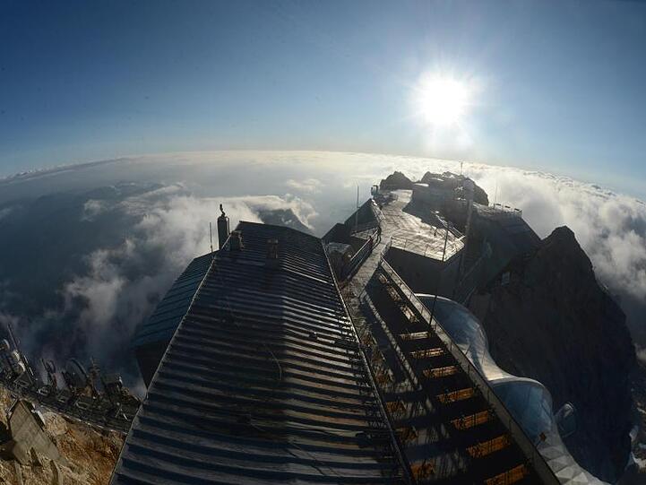 Das Münchner Haus, eine Alpenvereinshütte, ist auf der Zugspitze kurz nach Sonnenaufgang vom Turm der Wetterstation aus zu sehen. Foto: picture alliance / dpa / Archivbild