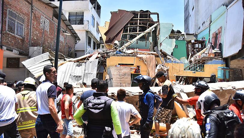 Anwohner und Rettungskräfte stehen vor zerstörten Gebäuden in Machala.