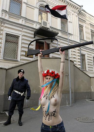 Nacktprotest mit blanker Brust und Gewehr.