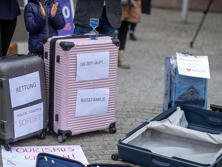 Mit leeren Koffern stehen Besitzer und Mitarbeiter aus Reisebüros bei einer Protestaktion. Foto: Jens Büttner/dpa-Zentralbild/dpa