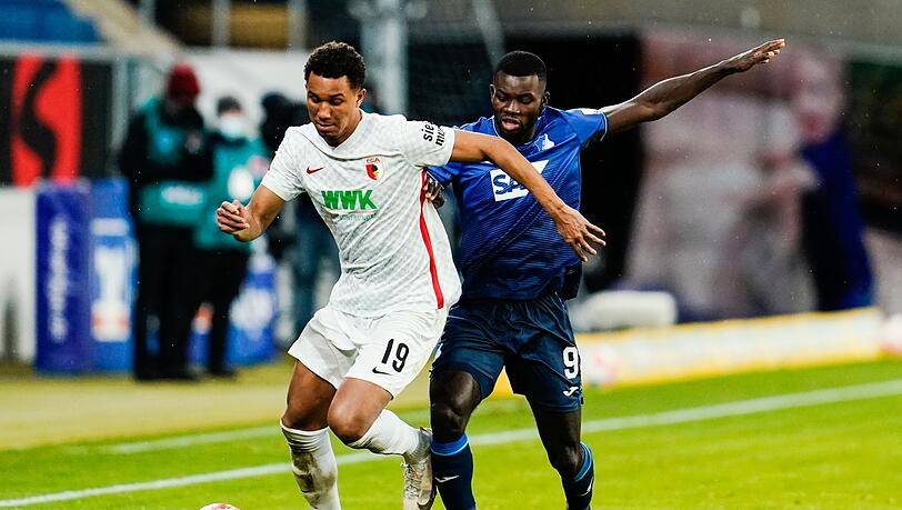 Augsburgs Felix Uduokhai (l) und Hoffenheims Ihlas Bebou kämpfen um den Ball.